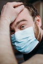 Sad balding adult man in a medical mask holding his head with his hands. Royalty Free Stock Photo