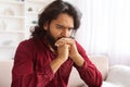 Sad bearded indian man sitting on couch at home Royalty Free Stock Photo