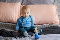 Sad, but beautiful blue-eyed baby sitting on the bed next to the toy pyramid Royalty Free Stock Photo