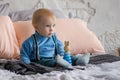 Sad, but beautiful blue-eyed baby sitting on the bed next to the toy pyramid Royalty Free Stock Photo