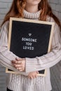 Sad beautiful woman holding felt letter board with the words Someone You Loved Royalty Free Stock Photo