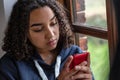 Sad or Depressed Biracial African American girl teenager young woman using her mobile cell phone for social media Royalty Free Stock Photo