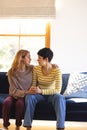 Sad biracial lesbian couple embracing, comforting and cheering up in sunny living room, copy space