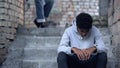 Sad black teenager sitting on stairs in gateway, problem of bullying at school Royalty Free Stock Photo