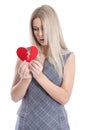 Sad blond caucasian woman holding broken red heart - love sickness. Royalty Free Stock Photo