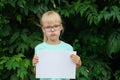 Sad blonde girl with glasses holding a blank sheet of paper with space for text Royalty Free Stock Photo