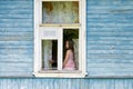 Sad bored little girl sitting on the sill and looking out the country house window Royalty Free Stock Photo