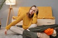 Sad bored tired Caucasian young adult woman feeling fatigue while packing suitcase at home for long time sitting on floor with Royalty Free Stock Photo