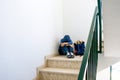 Sad boy with backpack sitting alone in the corner in the staircase Royalty Free Stock Photo