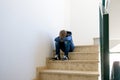 Sad boy with backpack sitting alone in the corner in the staircase Royalty Free Stock Photo