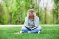 Sad boy with book on green grass Royalty Free Stock Photo