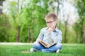 Sad boy with book on green grass Royalty Free Stock Photo