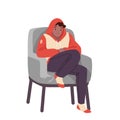 Sad boy in chair is cold in winter or autumn season, young man in hoodie, woolen socks