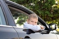The sad boy got out of the car window and looks away. Open car window Royalty Free Stock Photo