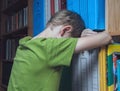 Sad boy leaning against a bookcase Royalty Free Stock Photo