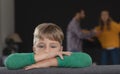 Sad boy leaning on sofa while parents arguing in background Royalty Free Stock Photo