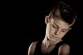 Sad Boy Looking Down Against Black with Copy Space Royalty Free Stock Photo