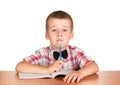 Sad boy with pen sitting at table on notebook isolated. Royalty Free Stock Photo
