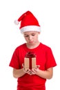 Sad boy, santa hat on his head, with the small gift box in the hands. Concept: christmas or Happy New Year holiday Royalty Free Stock Photo