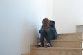 Sad boy sitting alone in the corner in the staircase Royalty Free Stock Photo