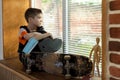 Sad boy is sitting near the window with his skateboard and medical safety mask during the quarantine Royalty Free Stock Photo