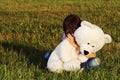 Sad boy sitting outdoors and hugging teddy bear