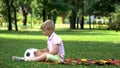 Sad boy sitting in park with football, lack of friends, victim of bullying Royalty Free Stock Photo