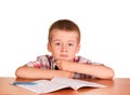 Sad boy sitting at table on notebook, pen isolated. Royalty Free Stock Photo