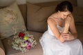 Sad bride sitting by bouquet on sofa at home Royalty Free Stock Photo