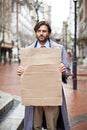 Sad, business and man with poster, unemployed in city and professional with stress and anxiety. Person, outdoor and Royalty Free Stock Photo