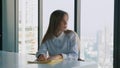 Sad business woman looking at folder with documents near the window