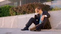 Sad businessman holds his head while sitting on the pavement after getting fired Royalty Free Stock Photo