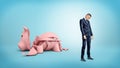 A sad businessman stands turned away from a giant broken piggy bank. Royalty Free Stock Photo