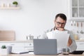 Sad busy mature caucasian businessman in glasses working with documents and laptop