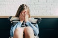 Sad Caucasian girl in depression hugs a pillow and closes her eyes with her hands on a background of a white brick wall. Thinks ab Royalty Free Stock Photo