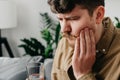 Sad caucasian male 30s sit on couch at home touching cheek, feel hurt and suffering from sensitive tooth ache. Pain and cavities Royalty Free Stock Photo