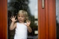 Sad child behind the window on rainy day