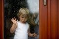 Sad child behind the window on rainy day