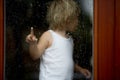 Sad child behind the window on rainy day