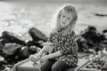 Sad child with a toy sitting on a vintage suitcase on the beach Royalty Free Stock Photo