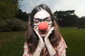 Sad clown girl with red nose at the park Royalty Free Stock Photo