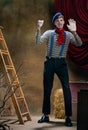 Portrait of male mime artist expressing sadness and loneliness over dark retro circus backstage background. Concept of