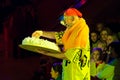 Sad clown is standing in audience among spectators and holding big birthday cake