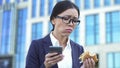 Sad company worker chewing tasteless sandwich holding smartphone hand, gastritis Royalty Free Stock Photo