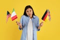 Sad confused young chinese female student in casual with many different flags look at camera Royalty Free Stock Photo