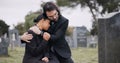 Sad couple, graveyard and hug in loss, grief or mourning together at funeral, tombstone or cemetery. Man holding woman