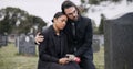 Sad couple, rose and graveyard in loss, grief or mourning at funeral, tombstone or cemetery. Man and woman hug with