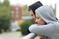 Sad couple of teens looking down in a balcony