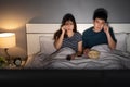 Sad couple watching television and crying on a bed at night romantic movie Royalty Free Stock Photo
