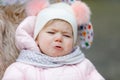 Sad crying hungry baby girl sitting in the pram or stroller on cold autumn, winter or spring day. Weeping child in warm Royalty Free Stock Photo